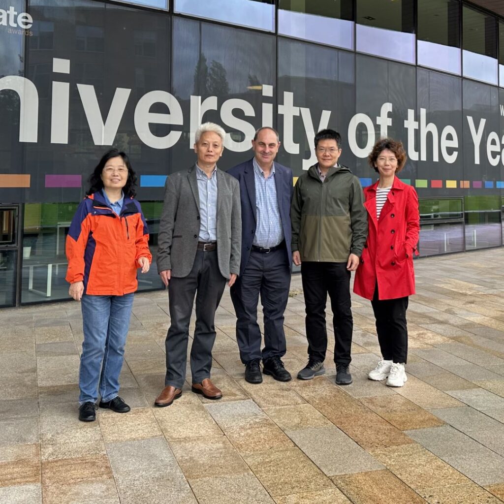 A picture of five people stood in front of a building.