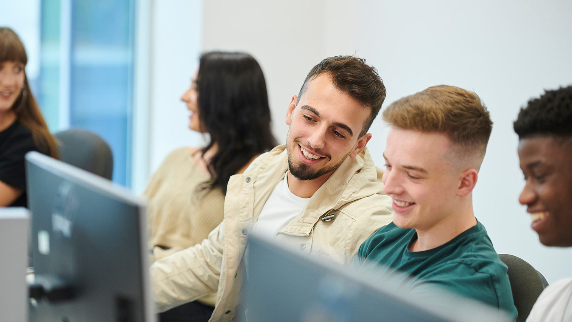 Students smiling and working at a computer.