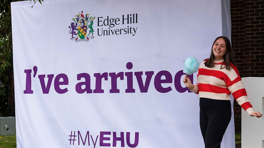 Student holding candy floss in front of an EHU Welcome Weekend sign.
