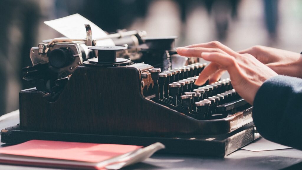 A person types on a typewriter. 2023 Edge Hill Short Story Prize.