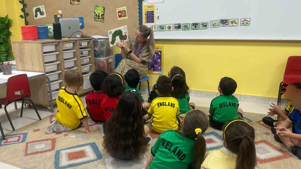 British School of Kuwait teacher reading a picture book to students.