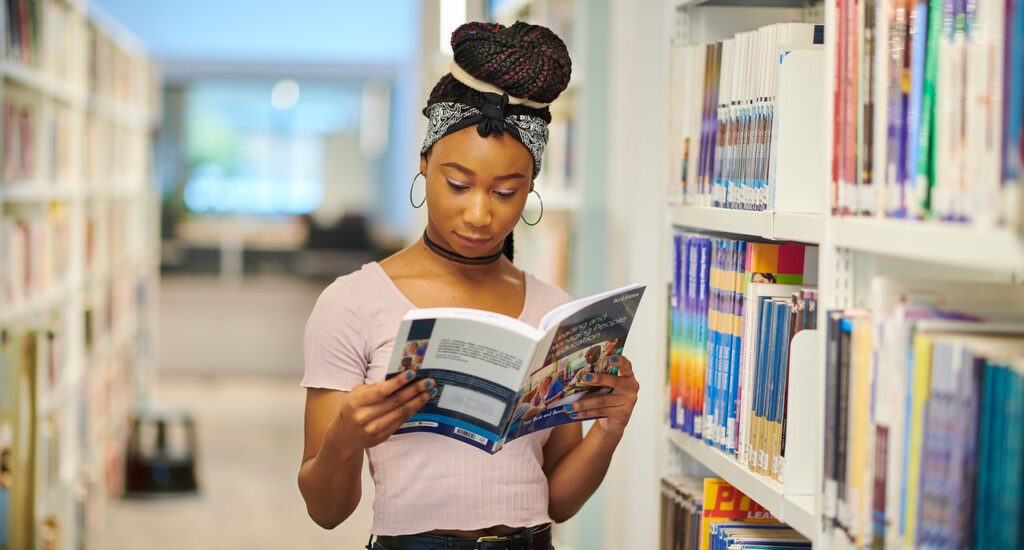 Student reading a book from the book shelf inside the catalyst.