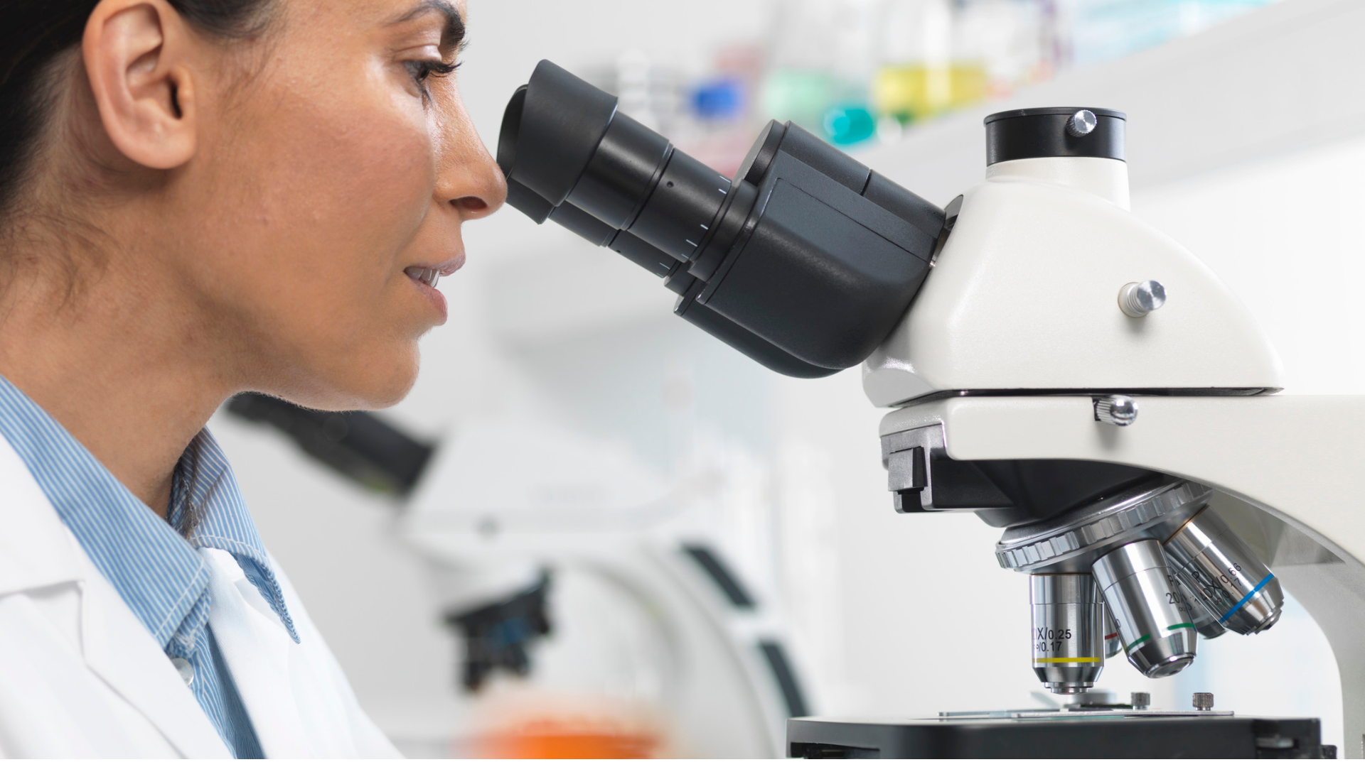 Technician in a lab using a microscope.