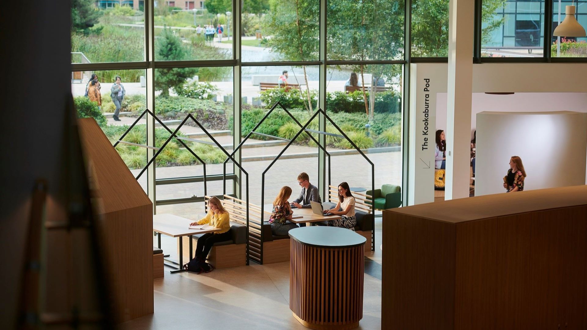 Students sit inside study pods in front of a huge floor to ceiling window.