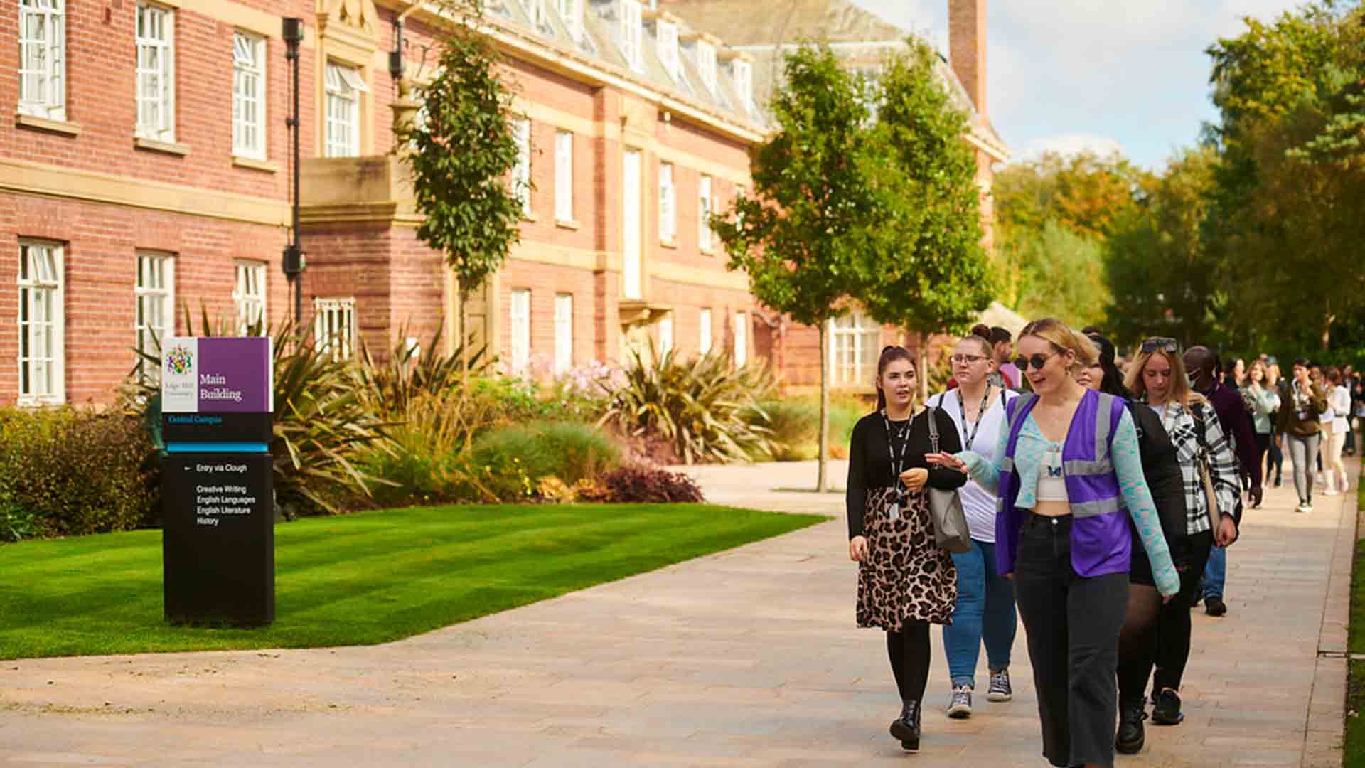 Student guide leading a campus tour, walking a group of students past Main Building.