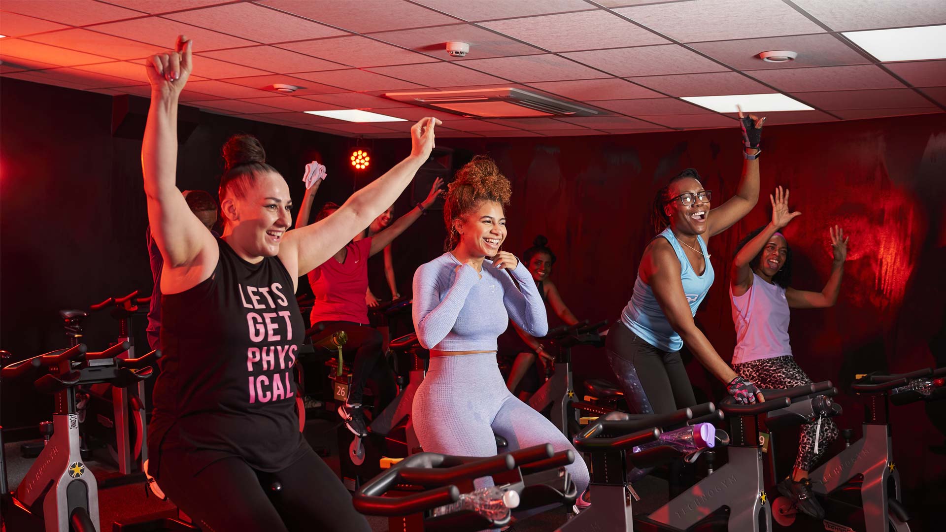 A group of people smiling and laughing during a spin class
