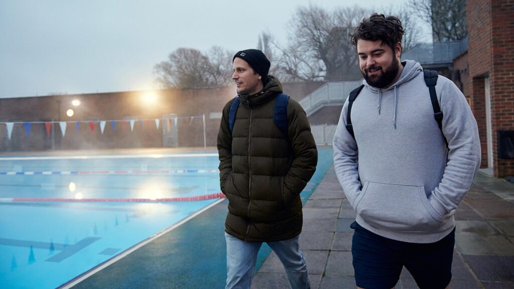 Two dads walk around a swimming pool