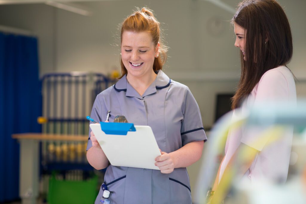 Student nurse in clinical skills talking to person posing as patient and taking notes