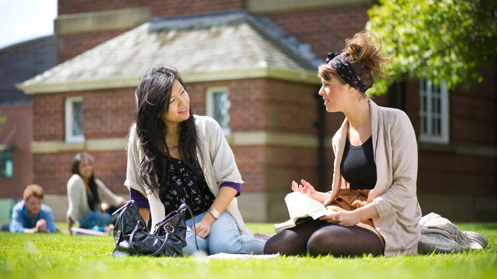 two international female students sat on the grass chatting