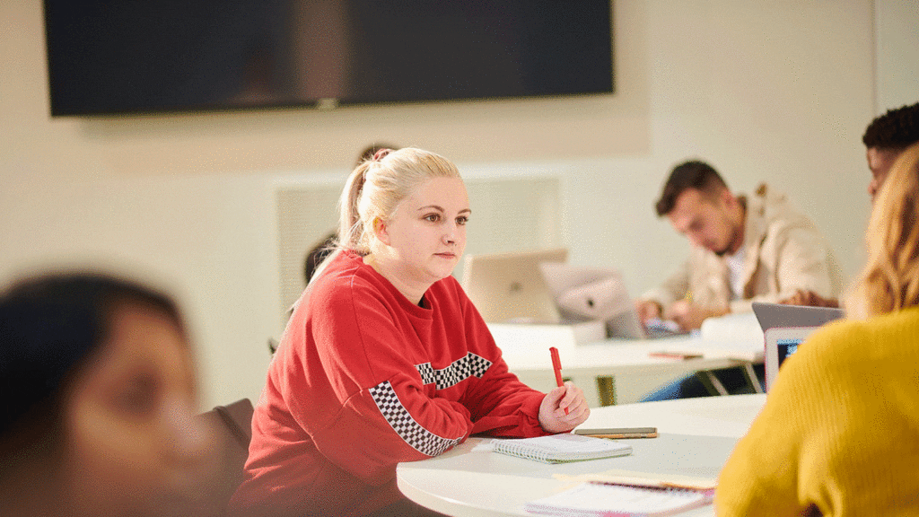 Image of student listening and prepared to take notes in a classroom.