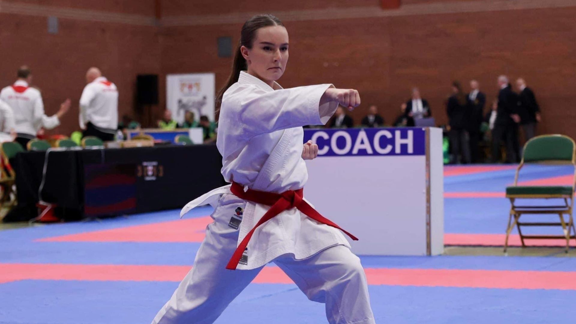 Grace in white karate robes in karate pose at competition in Venice