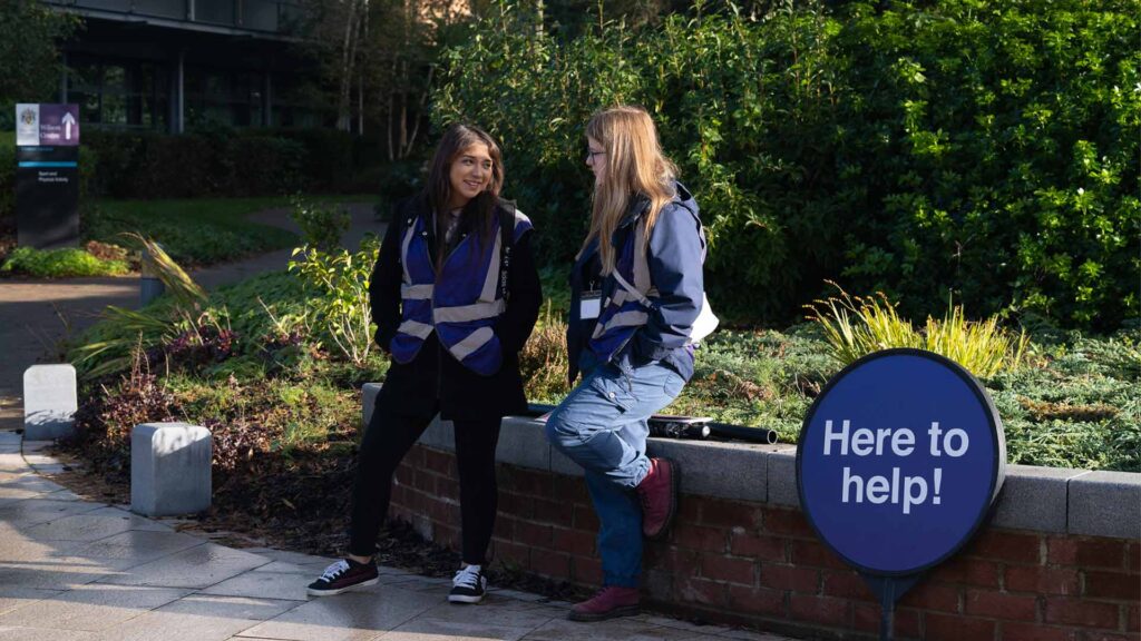 Image of two student guides chatting whilst helping visitors during open day