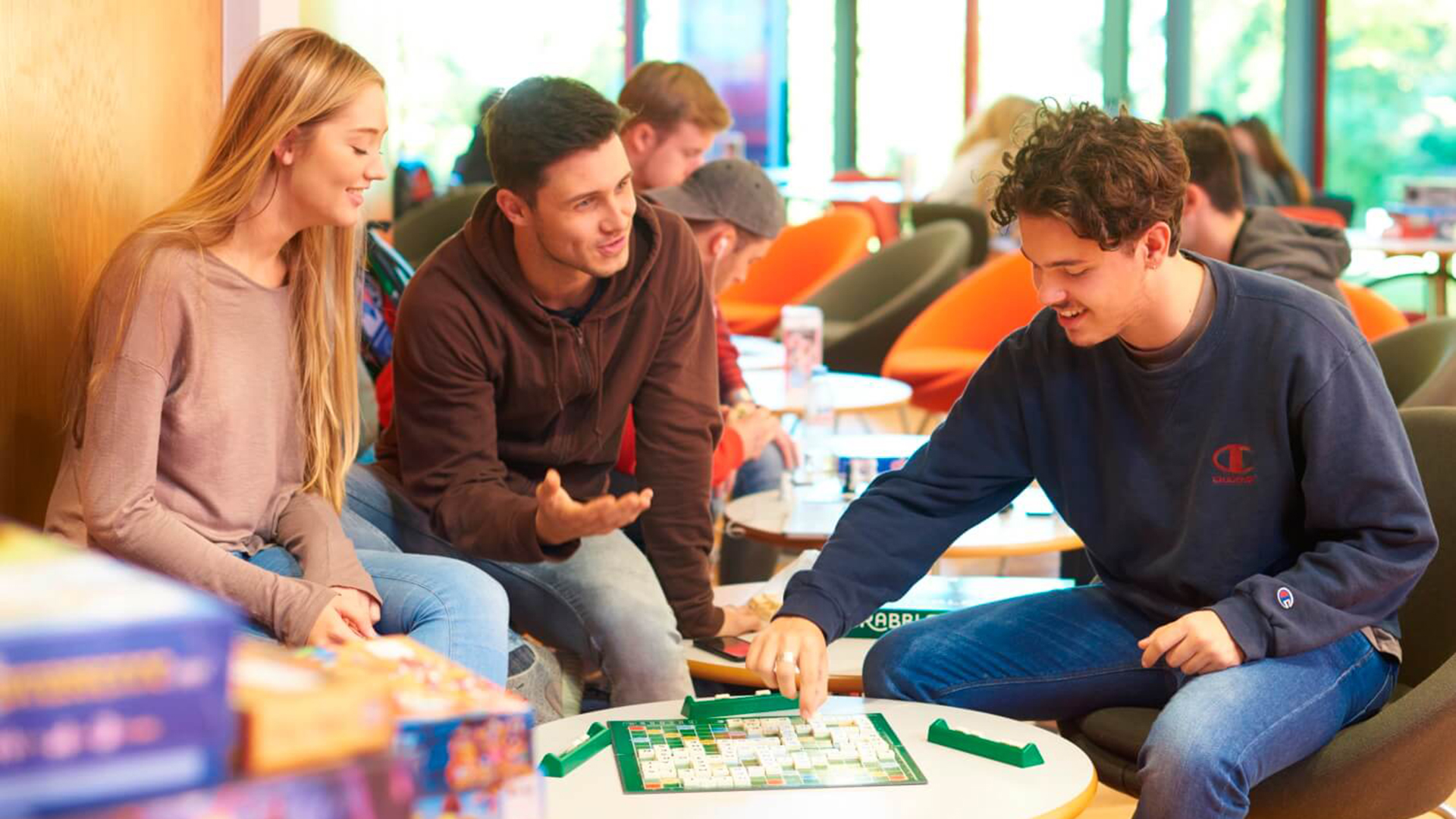 Three students play a board game at the Games Cafe in the Red Bar in the Arts Centre.