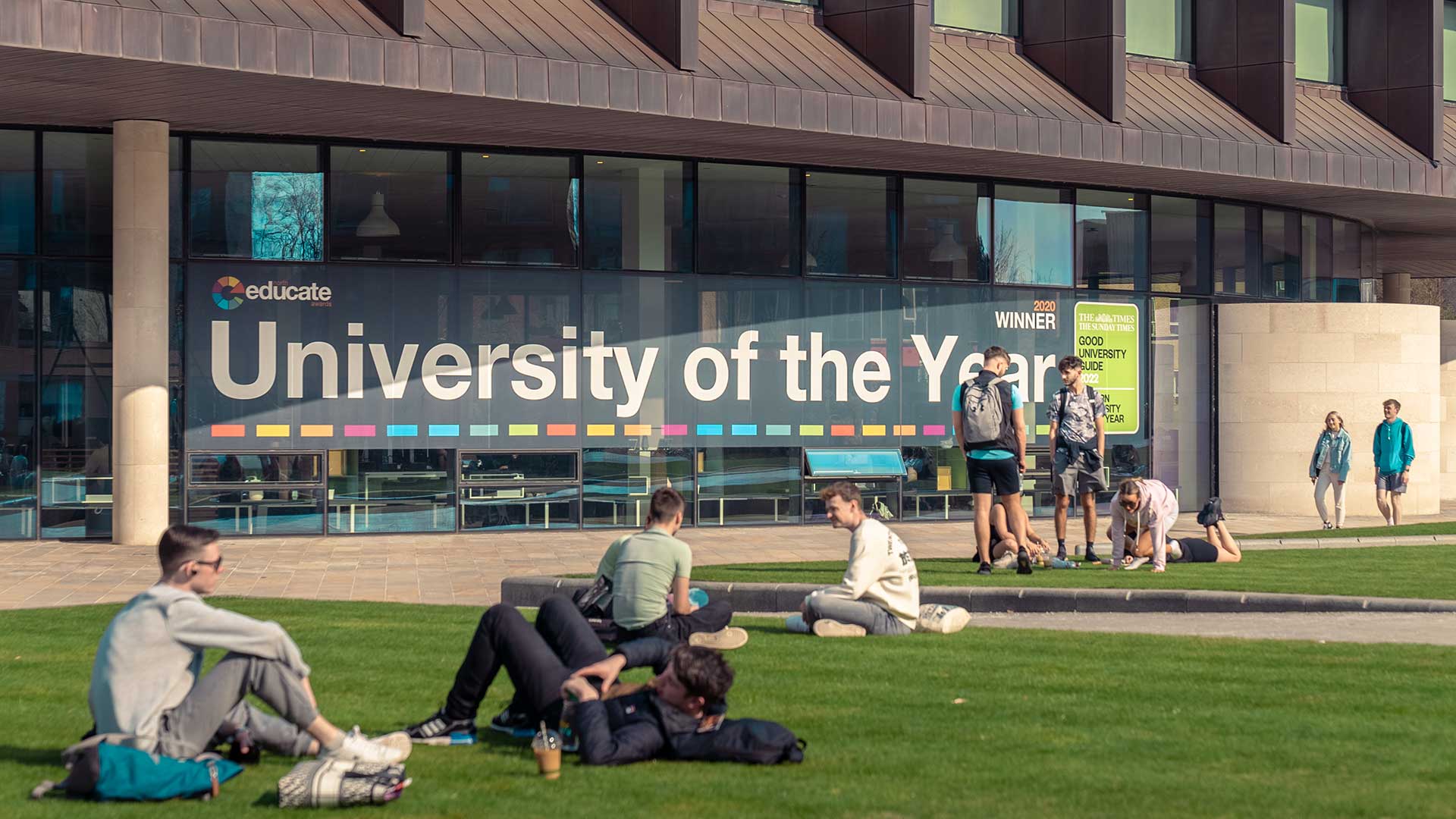 Students on campus green with Catalyst in the background.