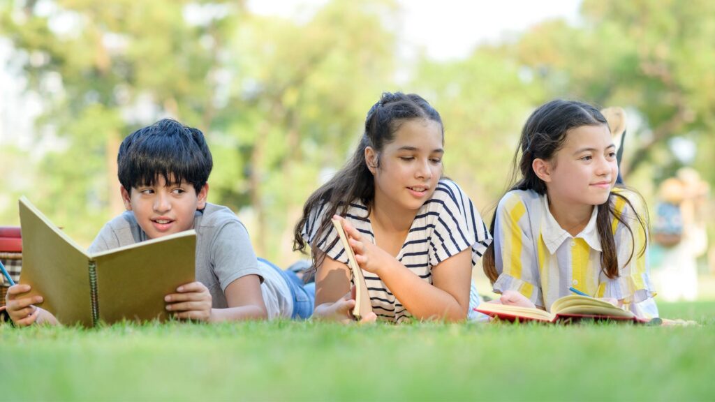 Three children reading on the grass