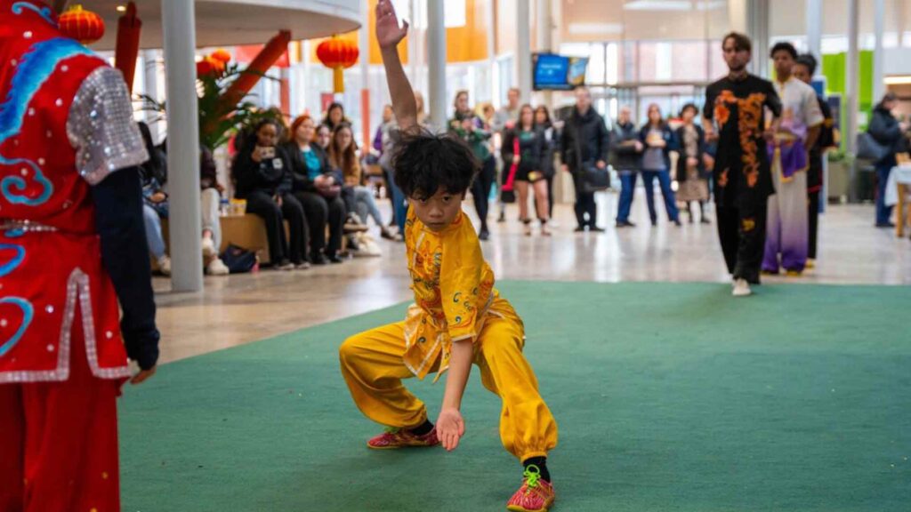 Performer taking part in martial arts, in a yellow suit, at the Chinese New Year event.