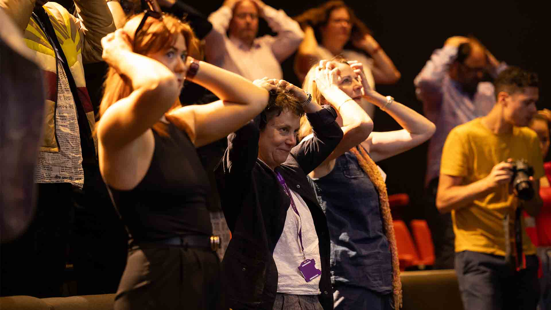 Students in the crowd stood with their hands on their heads at a RCAW event.