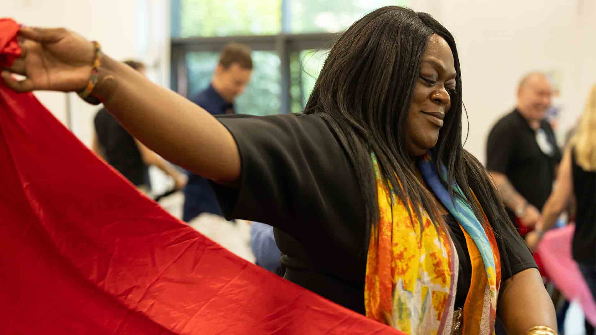 A student as part of a RCAW event, waving a red flag in a sports hall.