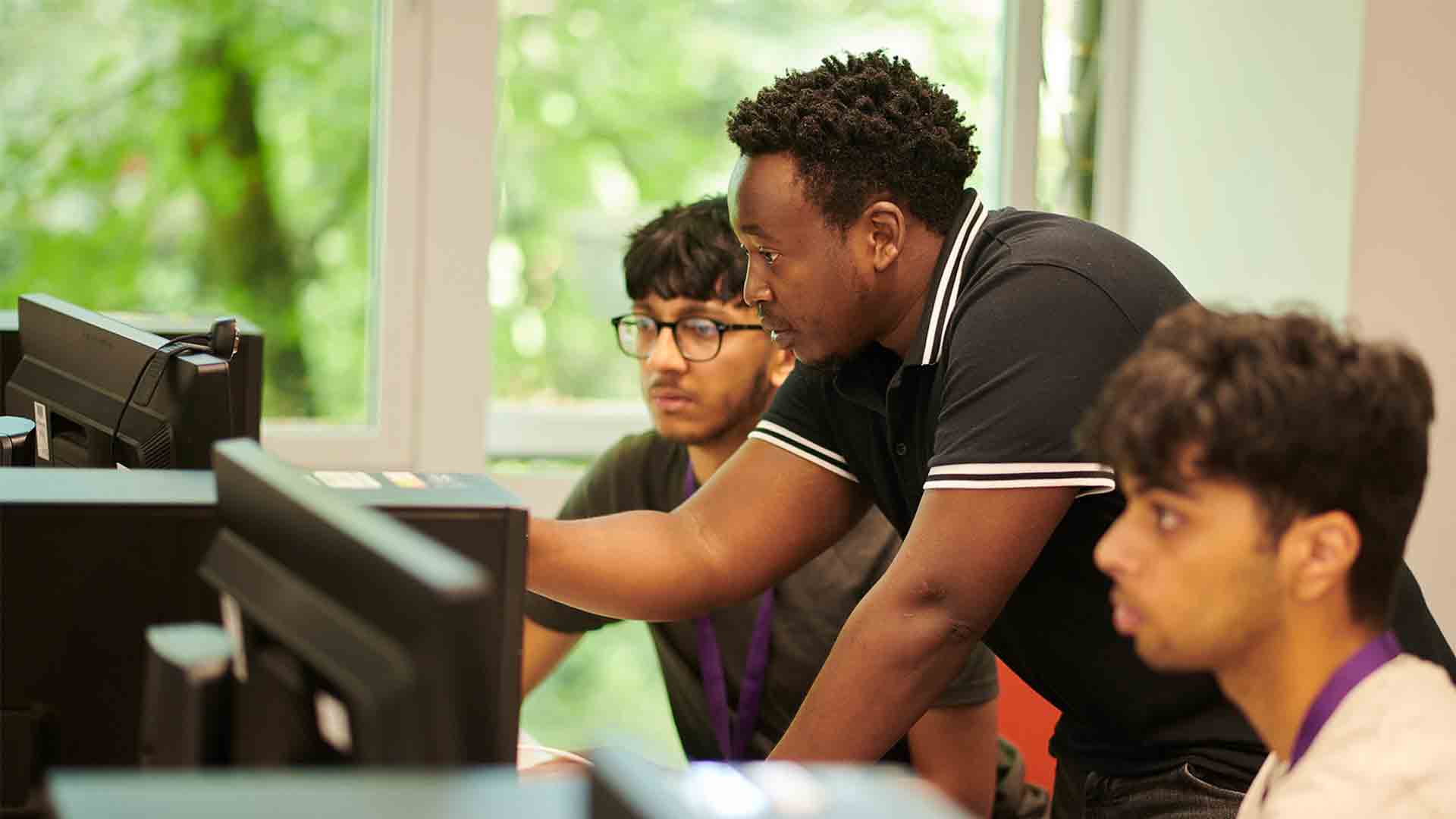 Staff member helping students on the computer.