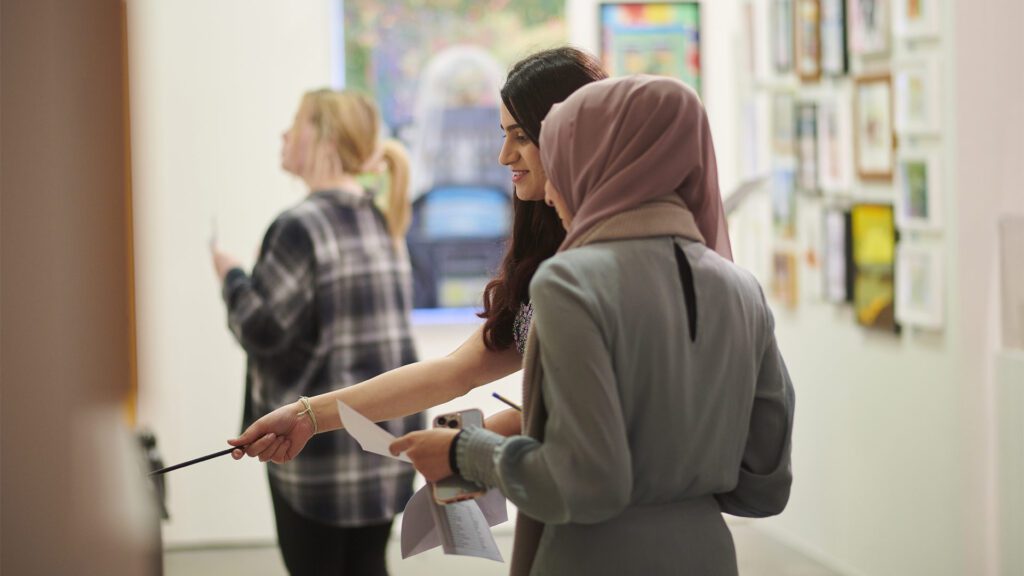 Students looking at paintings in a gallery exhibit