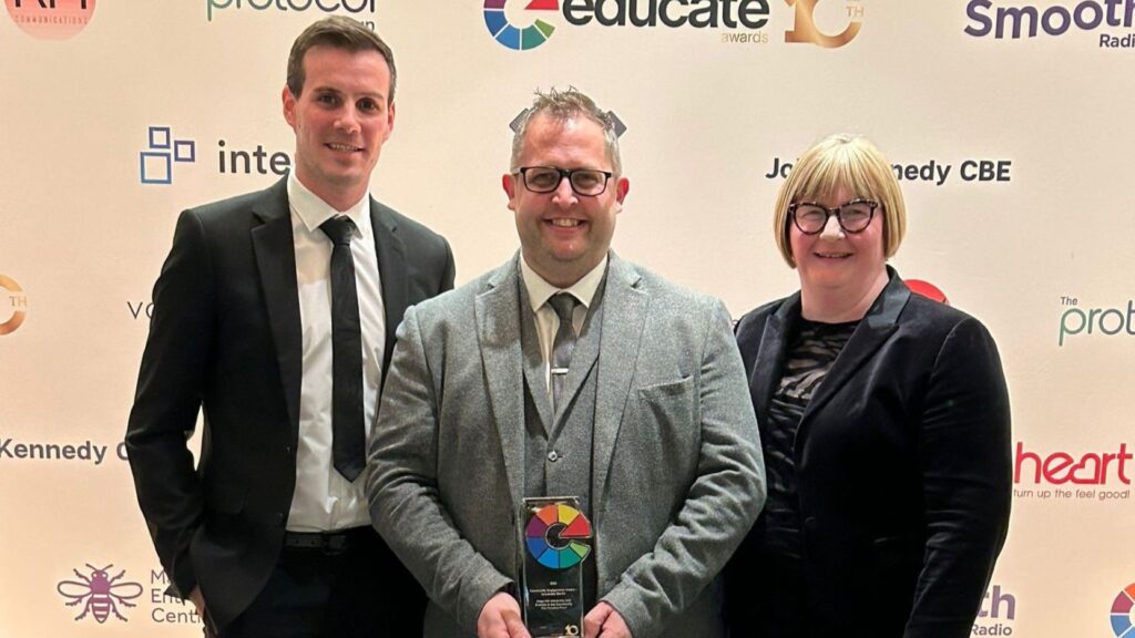 Three people stand in a line holding an Educate North award.