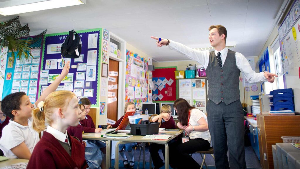 A trainee teacher speaks to a classroom of primary school students