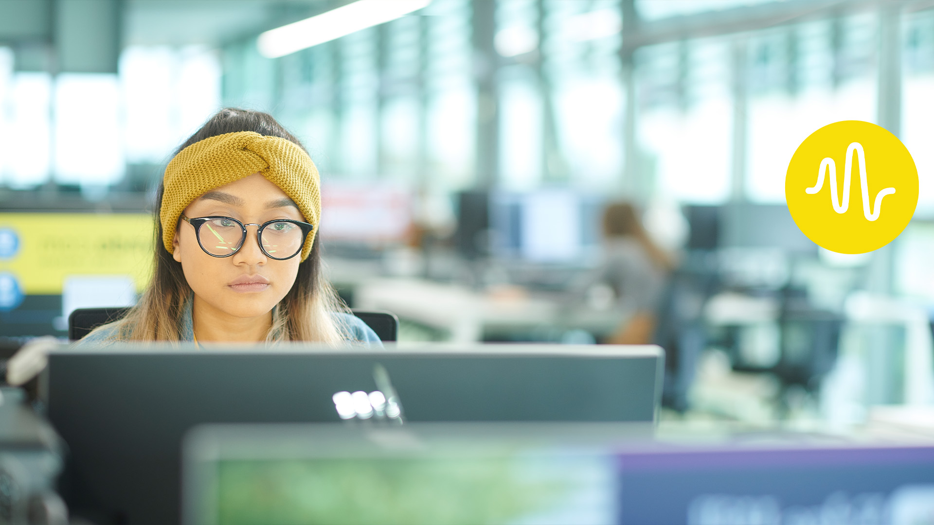 female student on a computer in catalyst with yellow student voice logo