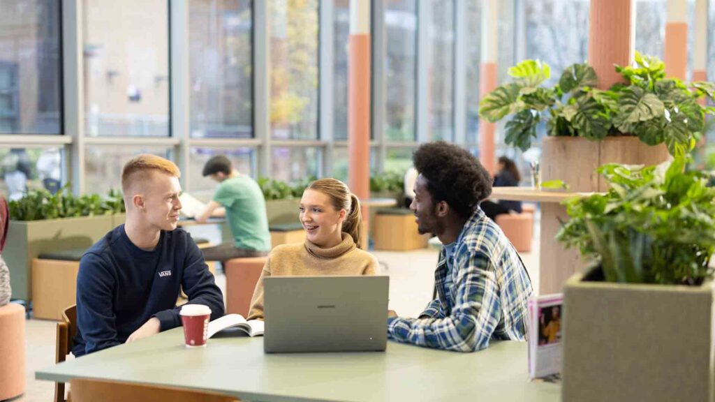 An image of three students sat working together in the Hub