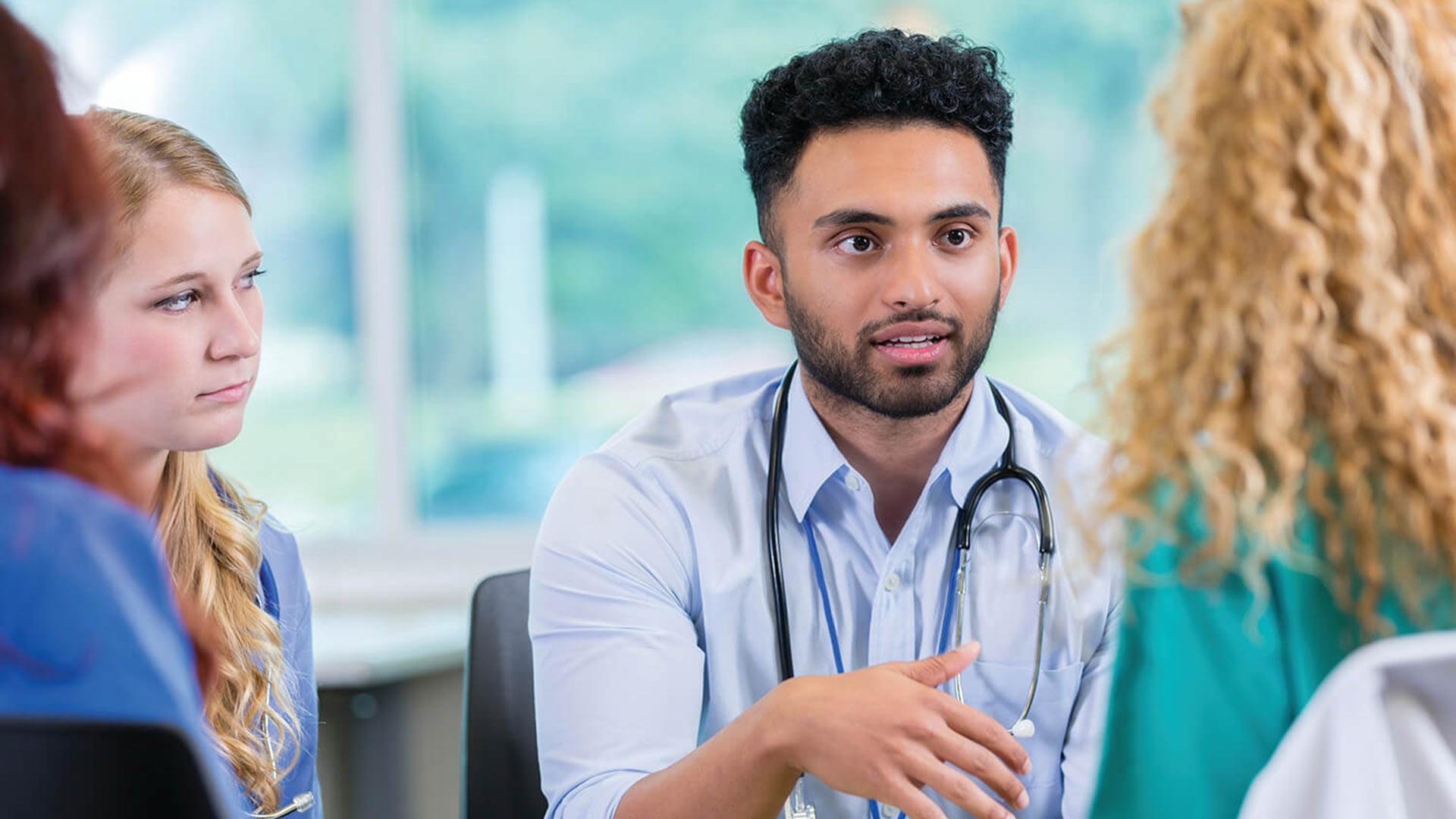 A doctor talks to colleagues during a meeting