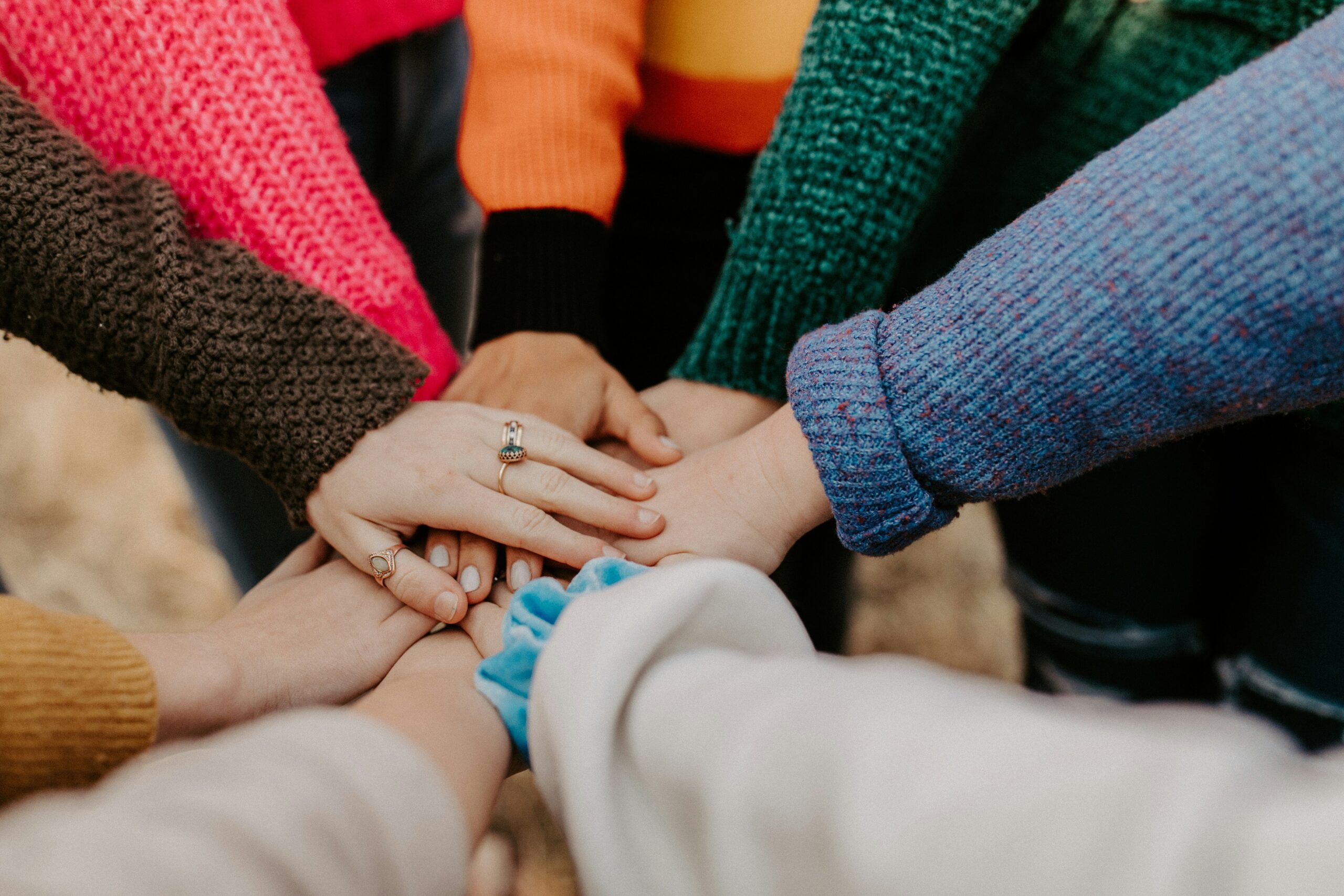 A photo of 8 hands on top of each other in a circle to represent support