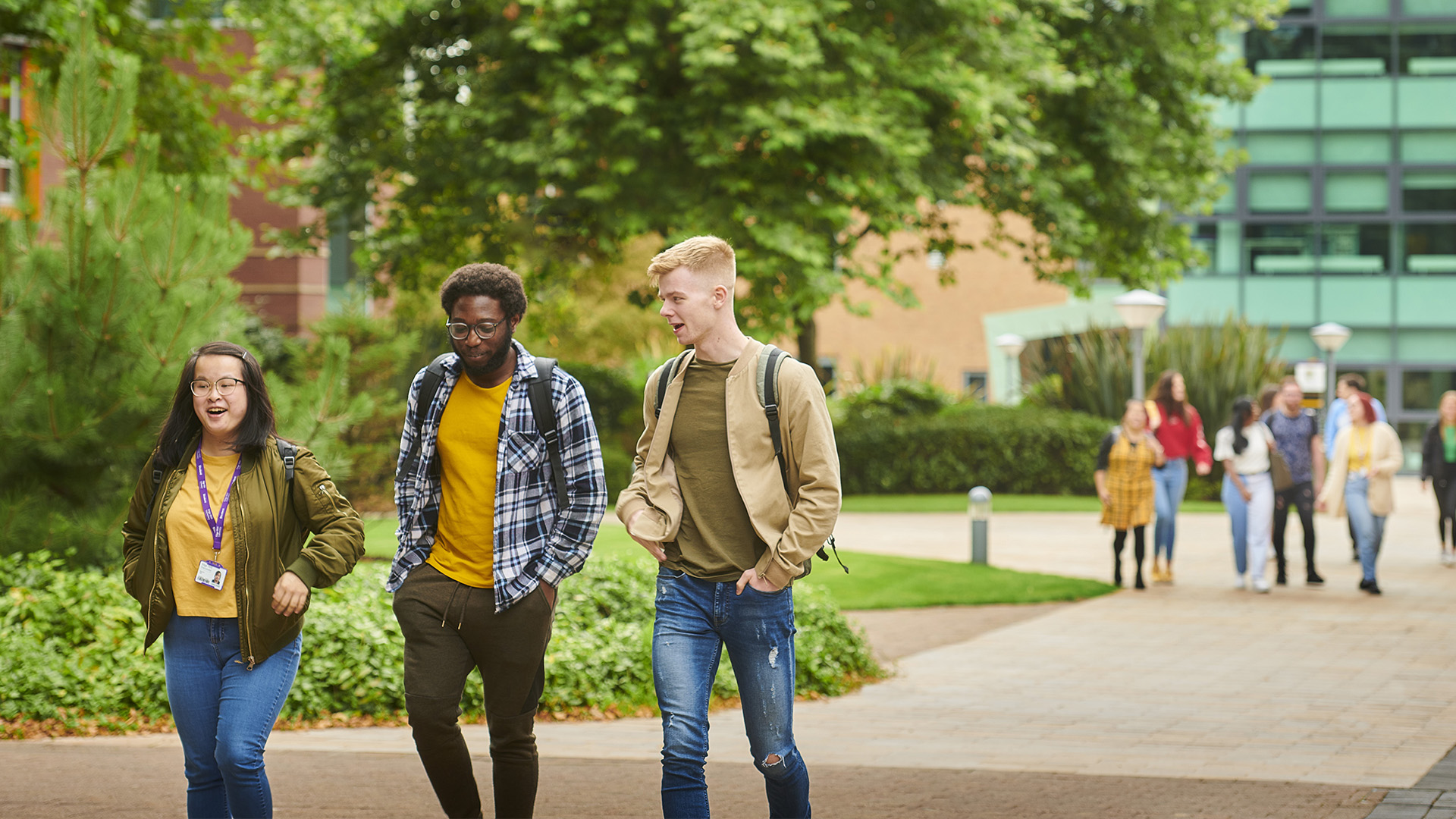 group of three students outside walking round campus