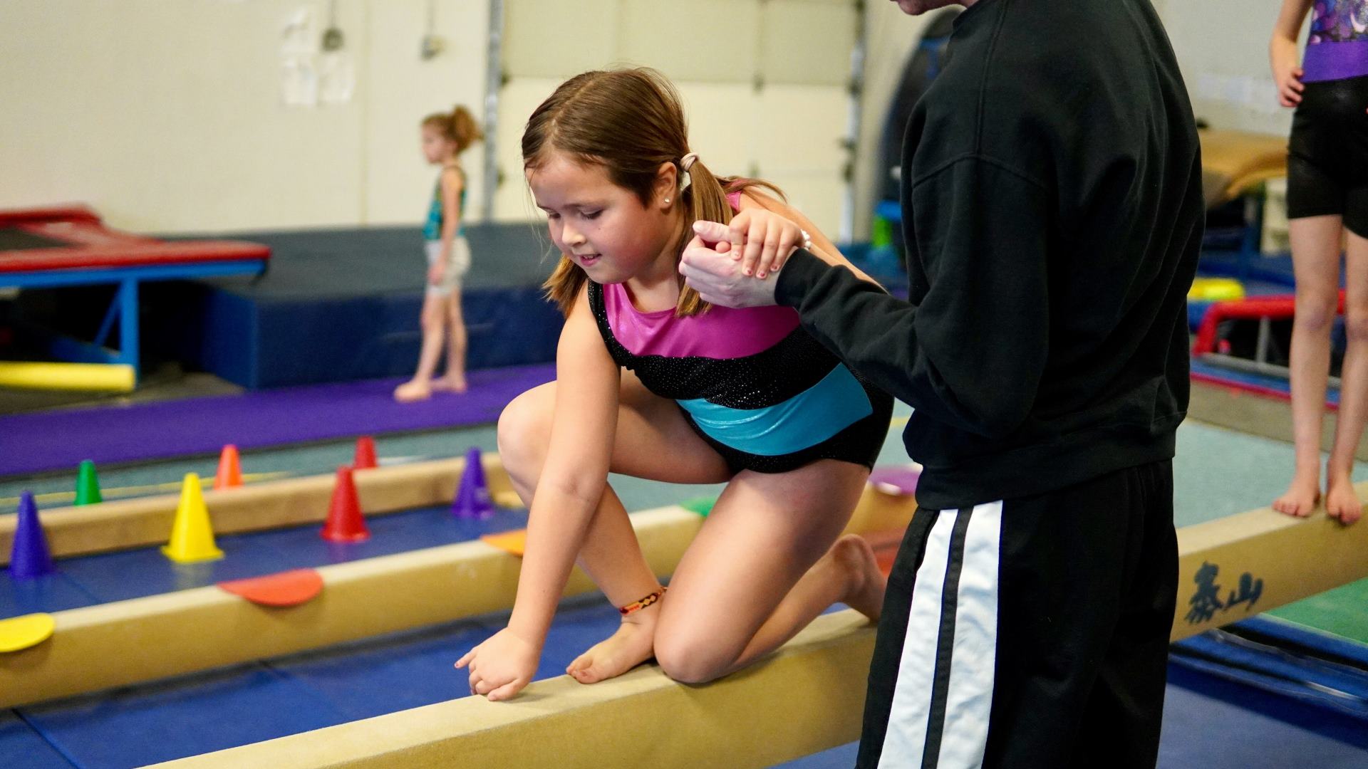 Young child working with a trainer in a gym.