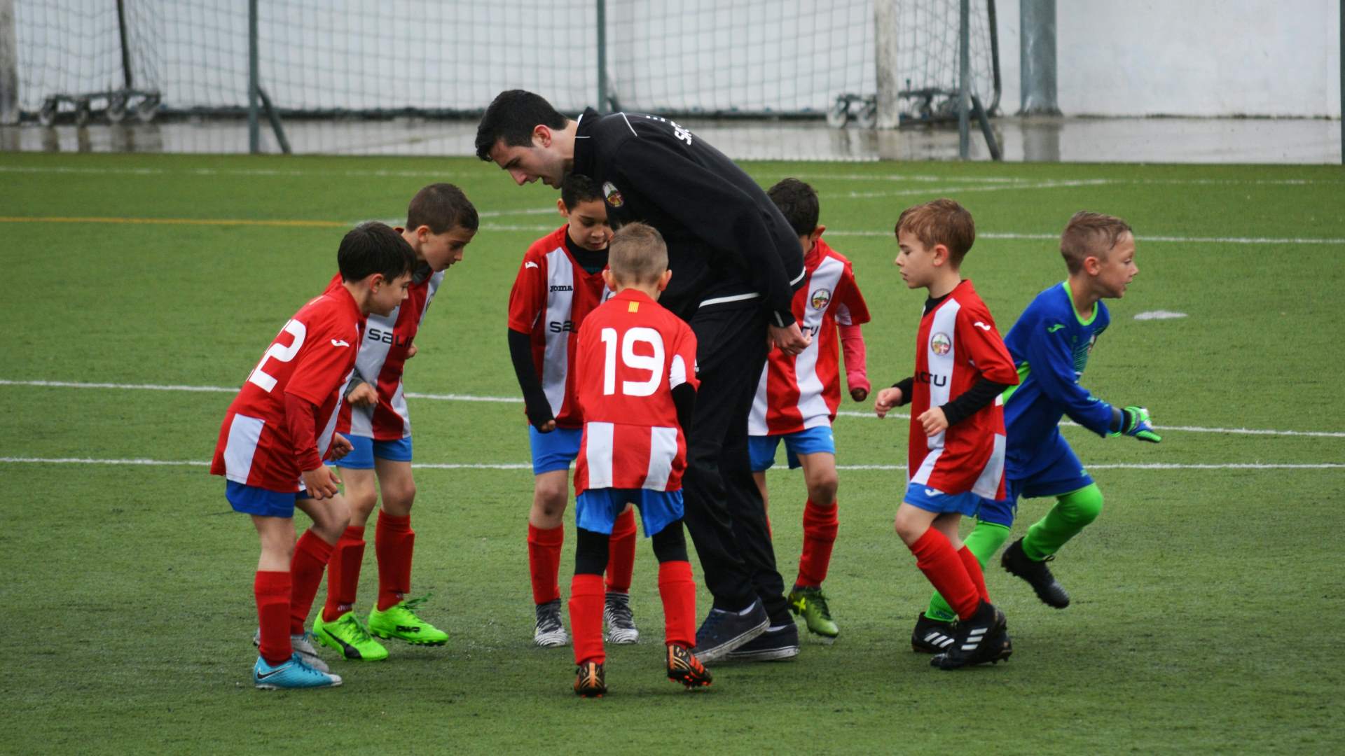 Children's football team listening to their coach.