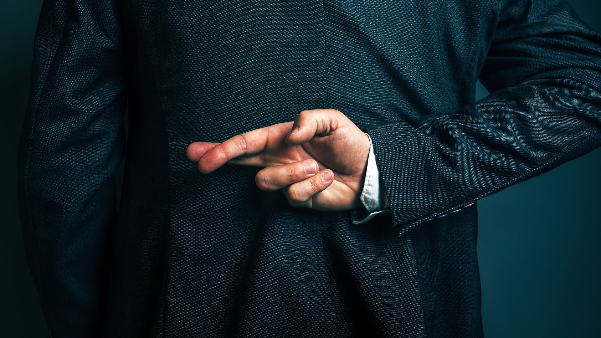 A man crosses his fingers and holds them behind his back.