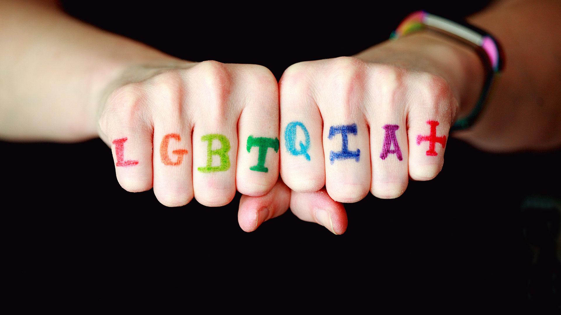 Hands withLQBTQIA+ in colourful writing