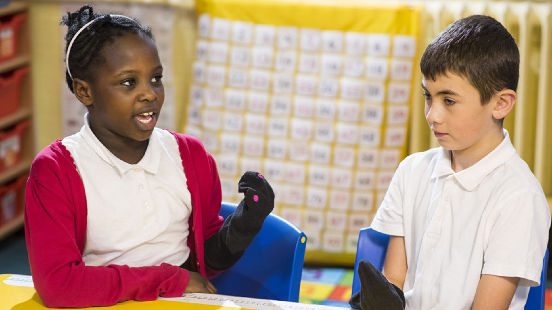 Children chatting through a numbers activity in the classroom.