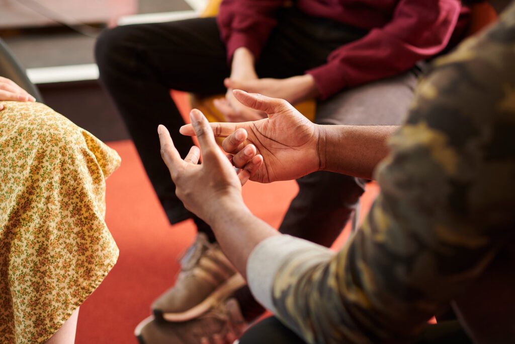Group of people sat in a circle, only their hands are on show.