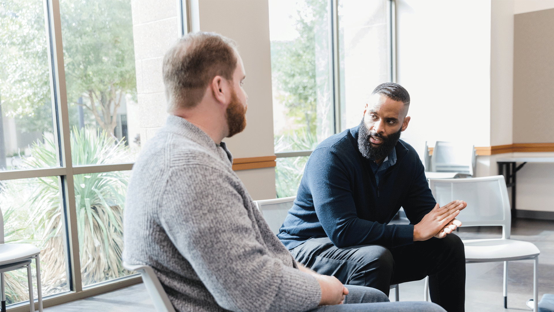 Two men sat on chairs in a conversation.