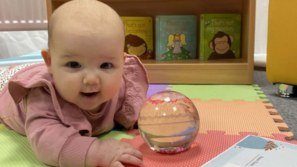 A photo of a baby playing with a ball
