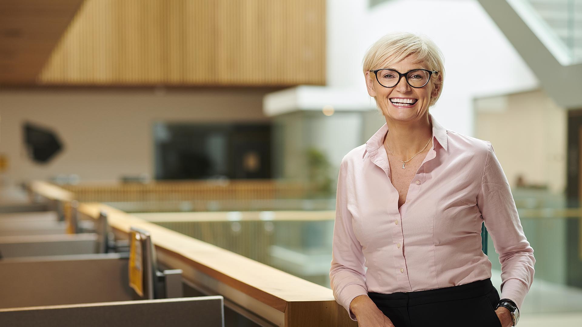 Bright photograph of future Interim Vice-Chancellor Lynda Brady smiling widely in front of study desks in Edge Hill’s Catalyst building