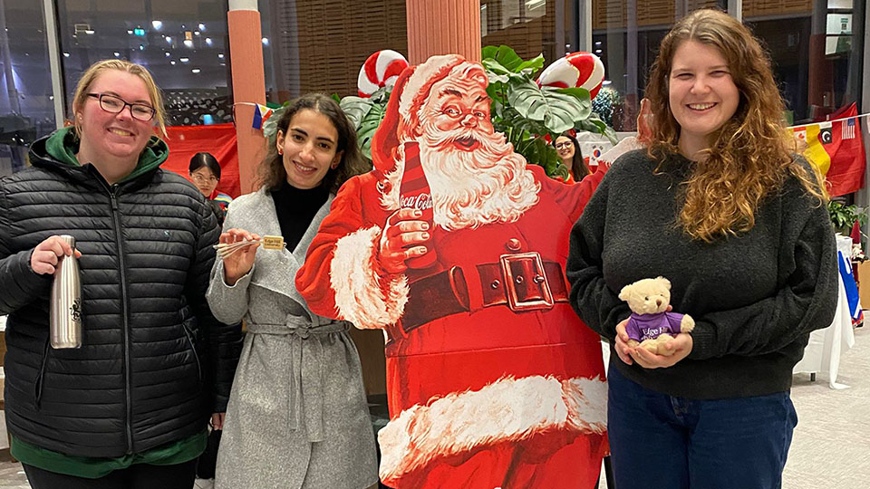 three students with santa cut out at a global cafe christmas special