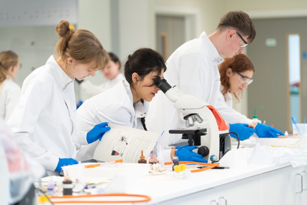 Students looking through microscope and using equipment in the Life Sciences building