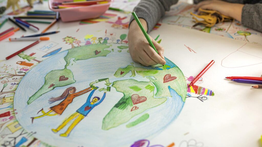 You can see a child hand holding colour pencils on a table with loads of colour pencil - the drawing is of a man and a women in the middle of the earth holding up a recycling sign