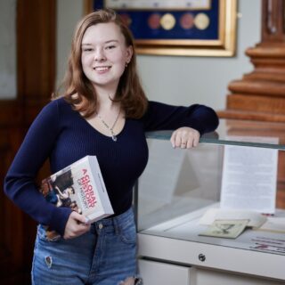 Student Katie Lagden profile photo stood up holding history book