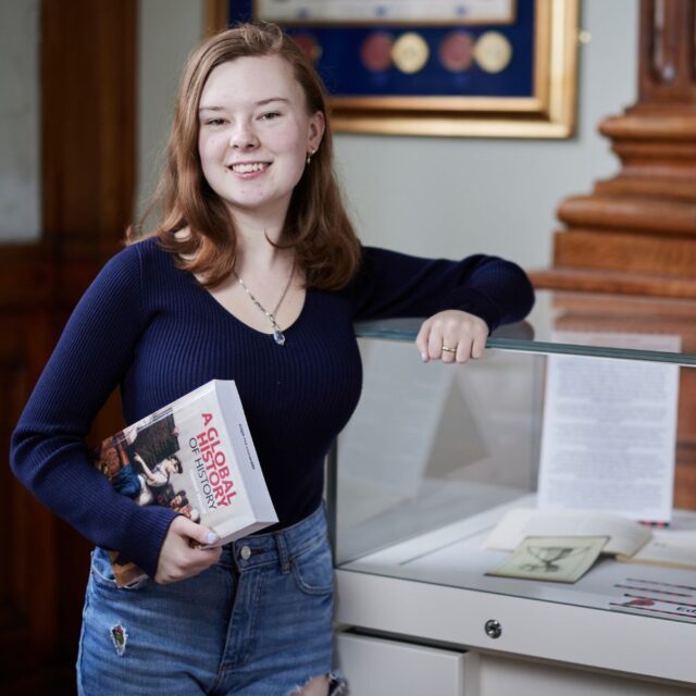 Student Katie Lagden profile photo stood up holding history book