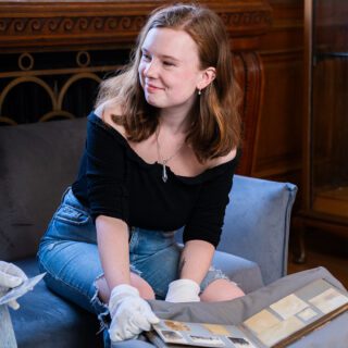 Katie Lagden smiling as she looks through historic artifact book