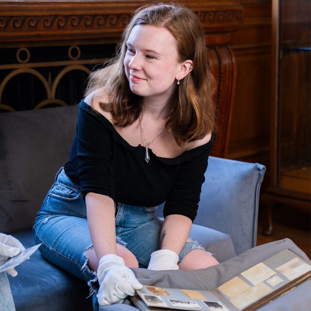 Katie Lagden smiling as she looks through historic artifact book