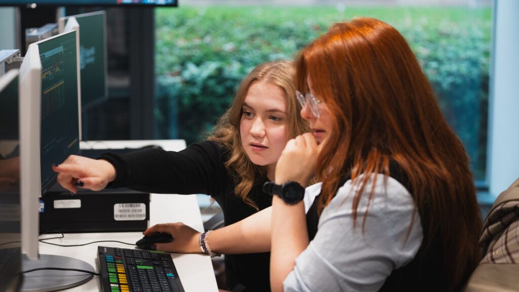 Students pointing at computer in the Bloomberg Suite