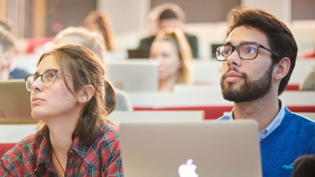 Two students sitting in a lecture theatre.