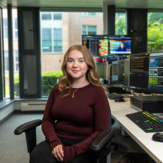 Charlotte Russell sat in the Bloomberg Suite. A computer screen is on display in the background